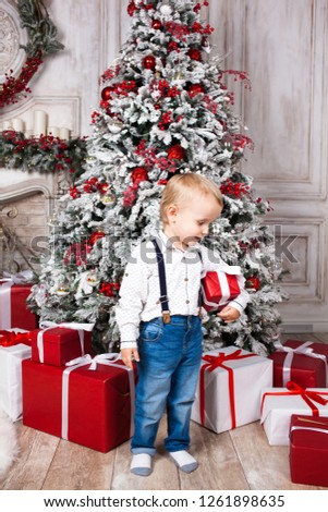 Happy little boy with toys and presents at home sitting near Christmas tree. Happy Family concept