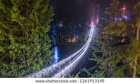 Vancouver, British Columbia - Canada. Long exposure at night, foggy view with Christmas lights of the Capilano Suspension Bridge. Vancouver. Beautiful British Columbia, Canada. Royalty-Free Stock Photo #1261913149