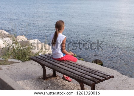 lonely girl sits on a bench and dreamily looks at the sea