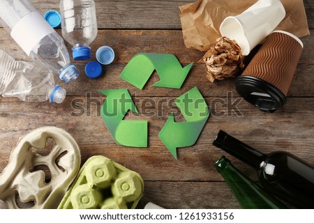 Recycling symbol and different garbage on wooden background, top view