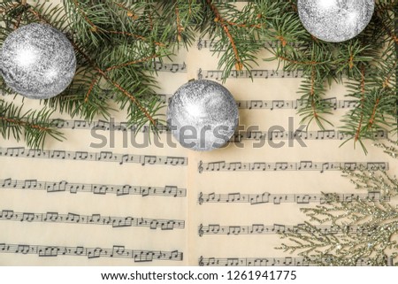 Composition with Christmas balls on music sheets, top view