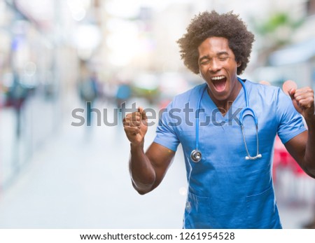 Afro american surgeon doctor man over isolated background celebrating mad and crazy for success with arms raised and closed eyes screaming excited. Winner concept