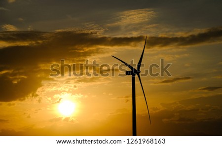 Wind turbine farm or windmill on golden sunset sky in summer day. High-quality stock photo image of wind turbine or windmill in a green field - Energy Production with clean and Renewable Energy
