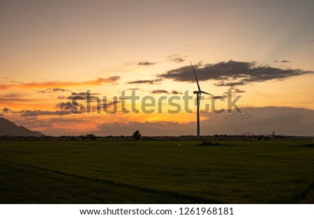 Wind turbine farm or windmill on golden sunset sky in summer day. High-quality stock photo image of wind turbine or windmill in a green field - Energy Production with clean and Renewable Energy