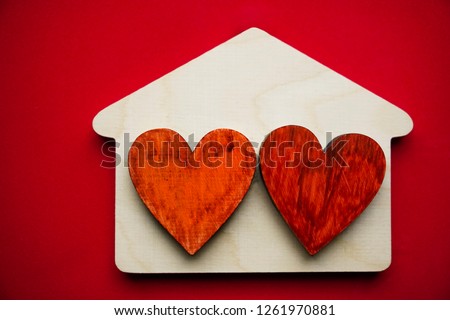 Symbol of love and fidelity - hand painted two red heart on wooden house on red surface.  space for text to the happy Valentines Day. 