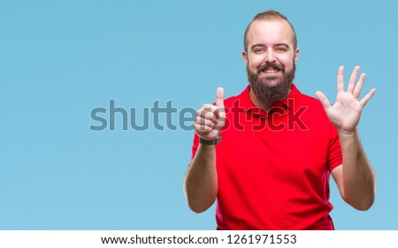 Young caucasian hipster man wearing red shirt over isolated background showing and pointing up with fingers number six while smiling confident and happy.