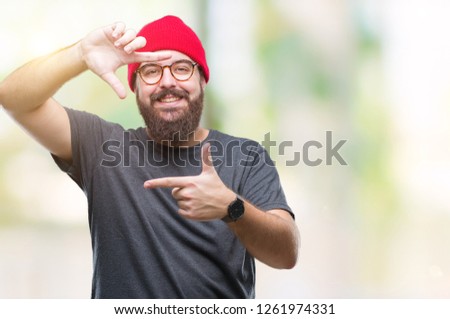 Young caucasian hipster man wearing glasses over isolated background smiling making frame with hands and fingers with happy face. Creativity and photography concept.