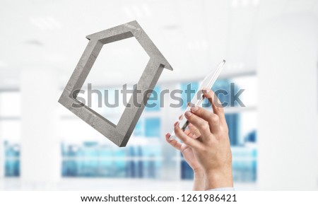 Cropped image of businessman in suit and stone house symbol in hands. Mixed media