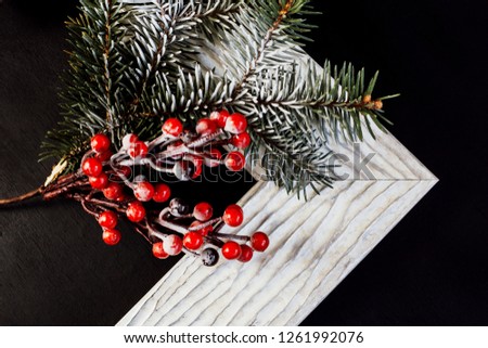 Picture frame with holly and pine branch on black background. Christmas concept.