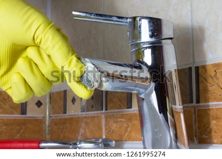 Hand in  yellow glove repairs faucet aerator,  limescale on  tap mixer.