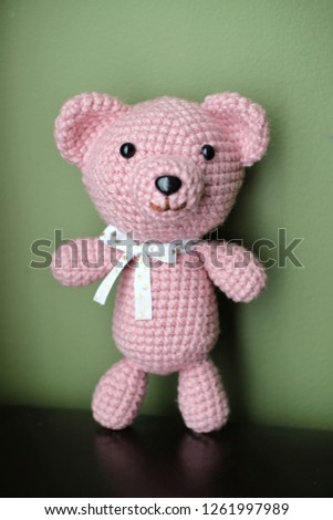 Pink crochet bear gift in green background picture for display, advertisement and content 