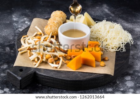 Wooden round board with tasty cheese on black background