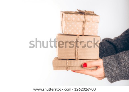 Woman in cozy knitted sweater holding christmas craft gift boxes. Giving presents concept.