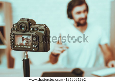 Blur Image of Blogger Makes a Video. Blogger is Gamer. Blogger is Man. Camera Shoots a Video. Man in Headphones Playing a Video Game on Computer. Man Looking and Pointing in a Camera. Studio Interior.