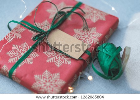 Christmas gift box against bokeh background. Holiday greeting card. Small Handmade gift box. Merry Christmas. New Year or Christmas Gift Box with Ribbon