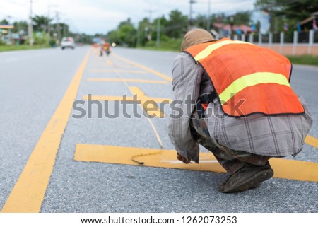 Worker painting the yellow line on the road. Road construction.