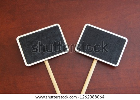 Two blackboard labels, chalkboard labels, garden marks or price tags on wooden background close up