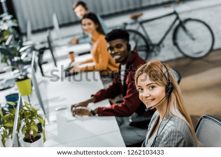 selective focus of multiethnic smiling call center operators working in office