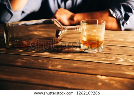 Alcoholic addict. Man near the table with empty bottle and a glass. Dangerous habit. Unhealthy life concept. Social problem. Economy crisis, poverty, unemployment concept. Consequences of coronavirus 