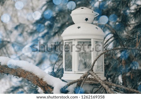 Winter, snow, white lantern on the snow-covered branch. Beautiful bokeh background
