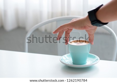 Woman hands holding blue coffee cups in cafe near the window. Lunch break background. With copy space