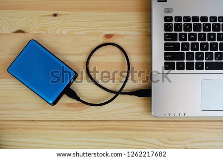 Portable external hard drive USB3.0 connect to laptop computer on wooden background