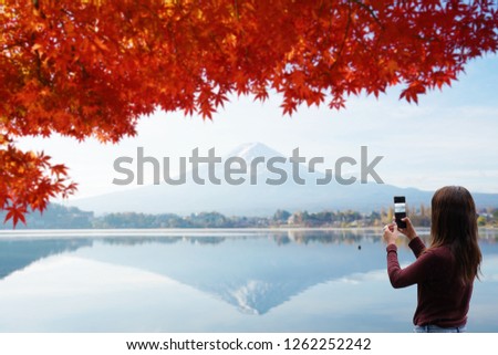 Tourist taking picture Mt.fuji with beautiful red maple.