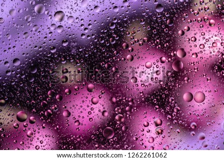 water drops on glass with purple and pink background, close-up 