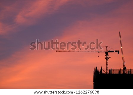 Crane and building construction site at sunset. High-quality stock photo image silhouette of construction tower crane group with sunset sky background. Building construction with crane during sunset