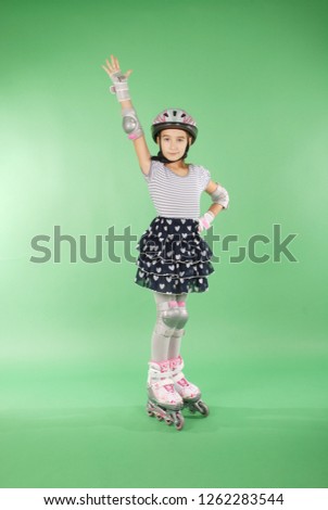 Pretty girl with rollerskates isolated against green background