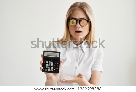 A woman wearing Bitcoin cryptocurrency glasses is holding a calculator in her hands                   