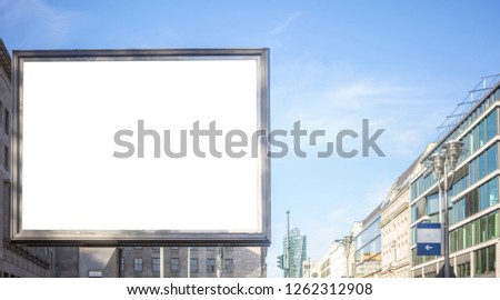 Blank billboard for public advertisement on the roadside. Space for text. Blue sky and city background. 