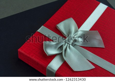 Beautiful Red gift box with bow black and grey background. Close up
