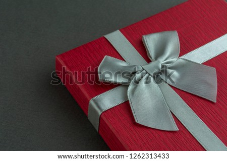 Beautiful Red gift box with bow grey background. Close up
