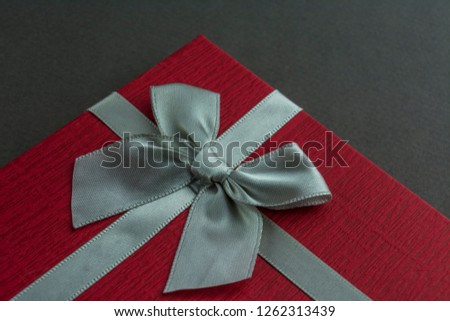 Beautiful Red gift box with bow grey background. Close up