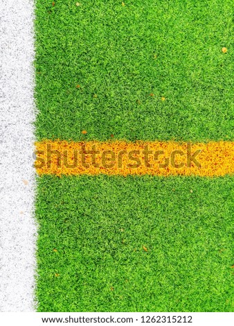 Green synthetic grass sports field texture with white and yellow line shot from above. Beautiful pattern of fresh green grass for football sport, football, soccer, team sport concept .