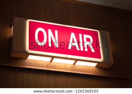 On Air sign icon glowing on the wooden wall of sound recording studios, live broadcast radio production room Royalty-Free Stock Photo #1262368105