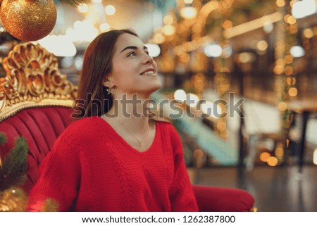 Pretty girl wear red, enjoing her time indoor Christmas place with lights. Copy space