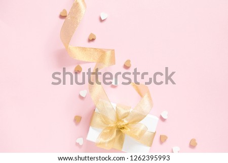 Elegant composition for Valentine's Day. Gift box with gold ribbon on pastel pink background. Valentine day concept, design. Flat lay, top view, copy space