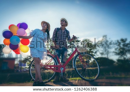 Young people with balloons and bicycles at sunset.