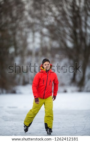 Young man ice skating outdoors on a pond on a freezing winter day