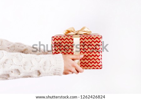 Female hands holding present with golden bow on white rustic background. Festive template for different holidays: Christmas, New Year, Birthday, Valentines day,. Close up, copy space.