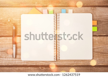 Blank notebook and pen on wooden background