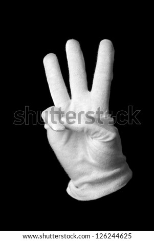Hand in white glove making sign isolated on black