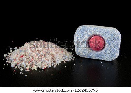 Powder and tablets for the dishwasher on the kitchen table. Cleaning agent for household dishwashers. Dark background.