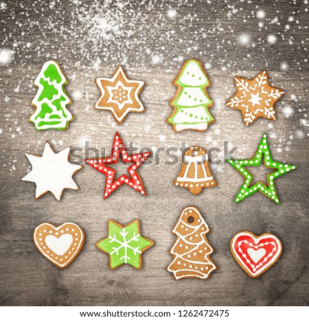 Christmas cookies of various shapes in sugar glaze on a cutting board on a brown wooden table sprinkled with flour, flat lay. Christmas composition with gingerbread men, fir-trees, rabbit.