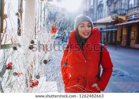 beautiful woman smile and talking near tradidional christmas tree wear warm red down jacket.  Christmas, new year and winter holiday concept