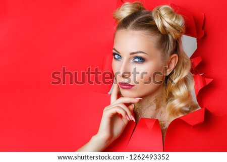 a beautiful girl in climbs out of a hole in red paper, a beautiful bright make-up, facial expressions of surprise and interest