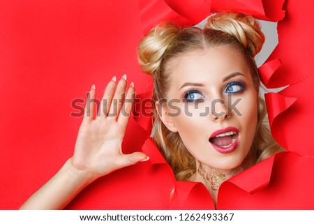 a beautiful girl in climbs out of a hole in red paper, a beautiful bright make-up, facial expressions of surprise and interest