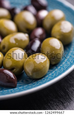 Green and dark olives on a blue greek plate.
